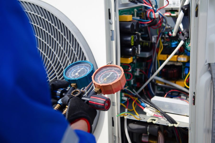 Engineer checking refrigerant pressure gauges on an air conditioning unit