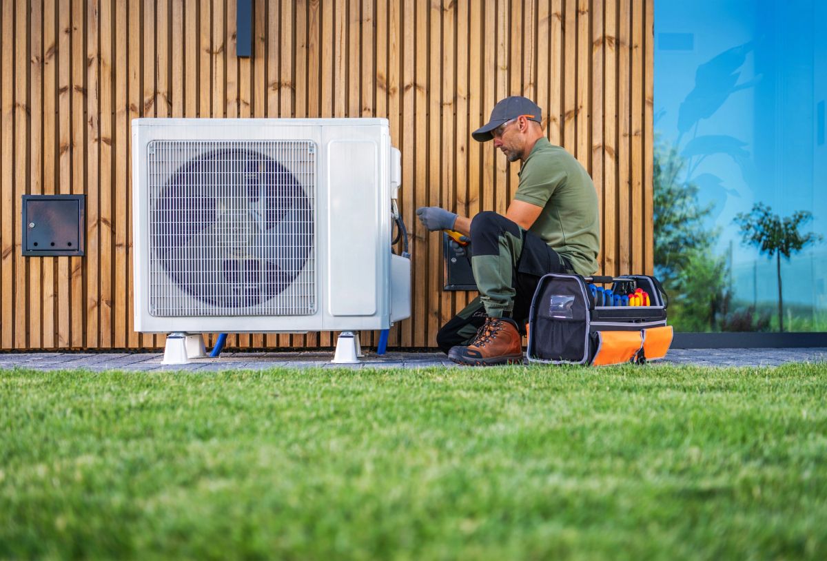 Engineer installing an air source heat pump outside a home