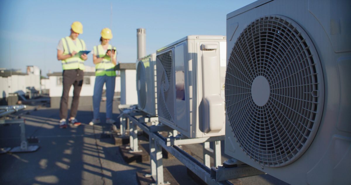 Rooftop air conditioning condenser units being inspected by two engineers