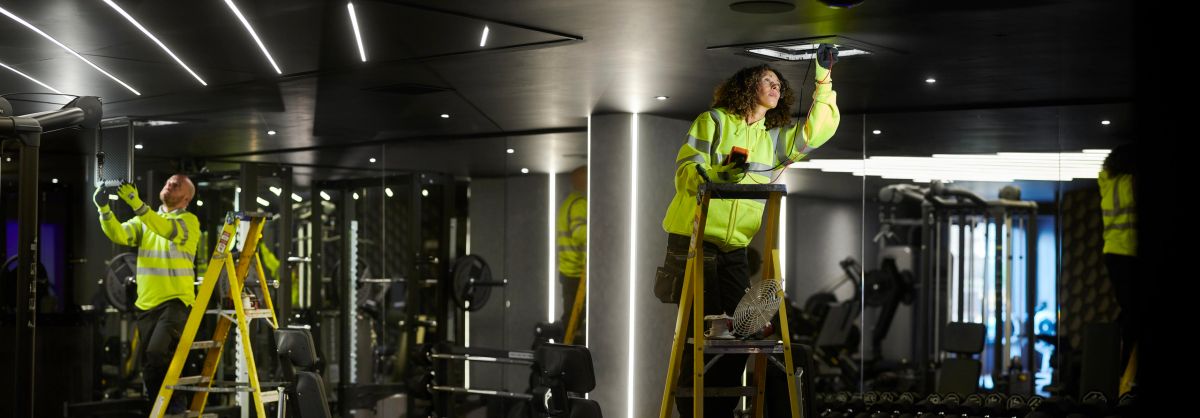Engineer installing ceiling ventilation in a gym
